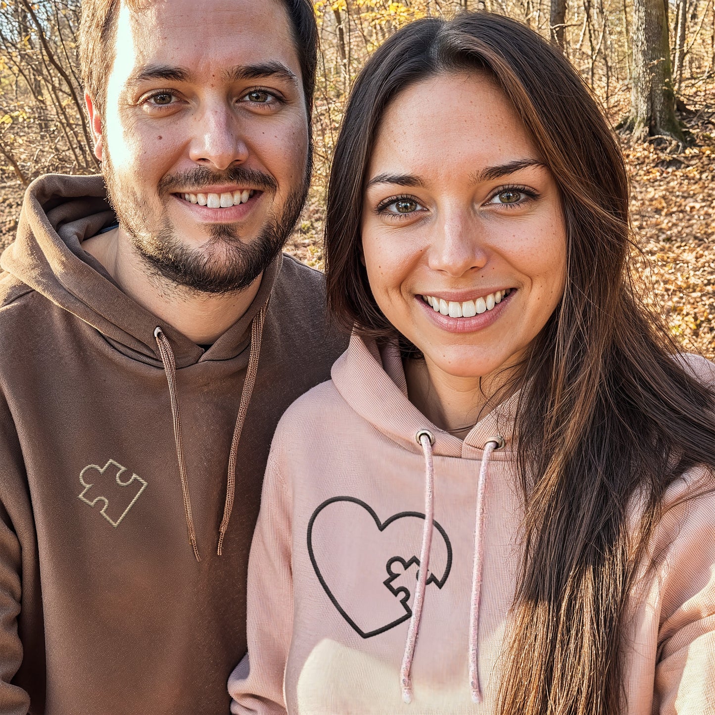 Selfie of a Couple wearing matching brown and pink hoodies with embroidered puzzle heart design