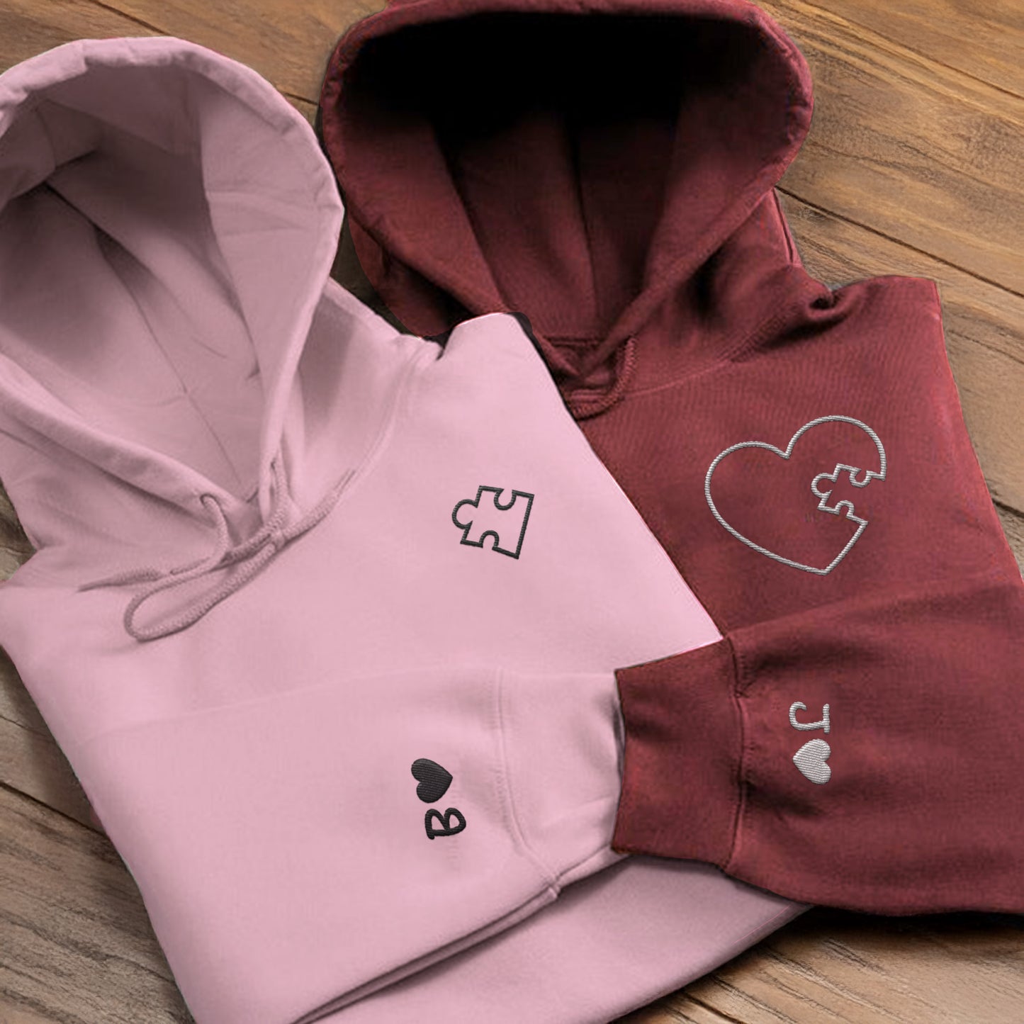 Matching pink and maroon hoodies for couples featuring embroidered puzzle heart design and initials