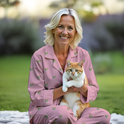 Woman wearing Custom pink pet pajama set with cat face design, holding orange tabby cat outdoors