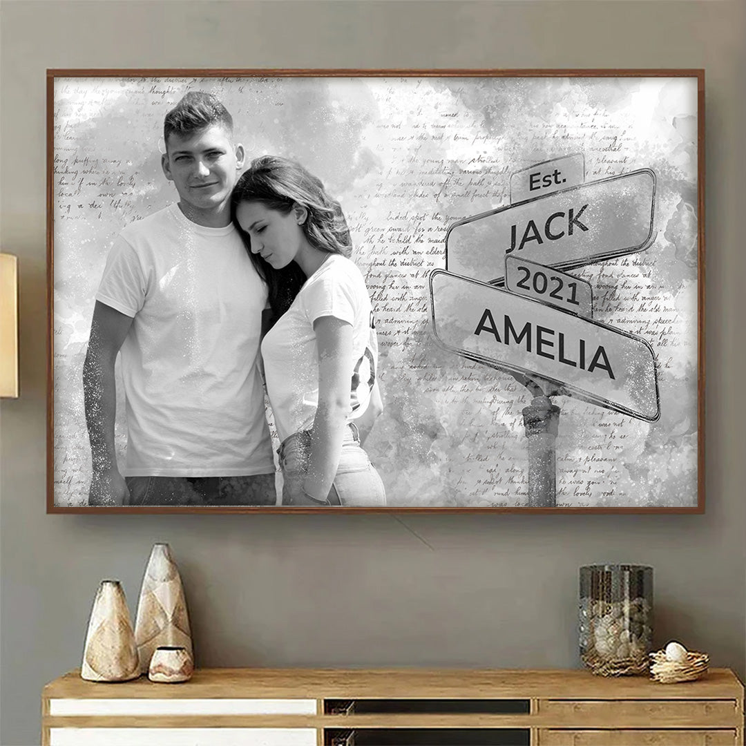 Couple in white t-shirts posing for a photo next to the street sign with their names and date